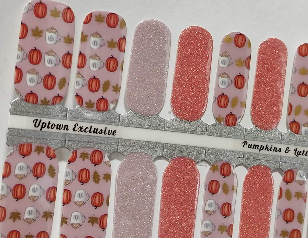 Nail wraps with a design that includes pumpkins and leaves in a fall color palette, with some wraps having a glitter finish.